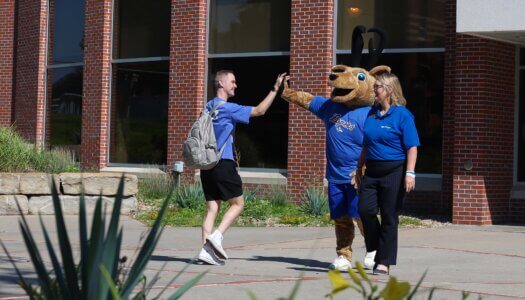 Louie the Loper high fives a student.
