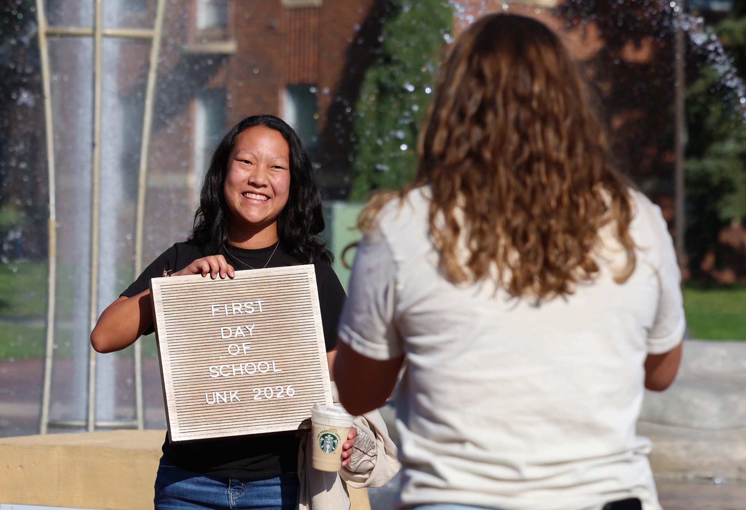 A student poses with a first day of school sign.