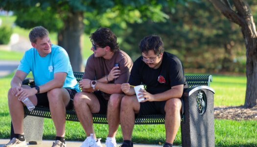 UNK students chat while sitting on a bench at Yanney Park.