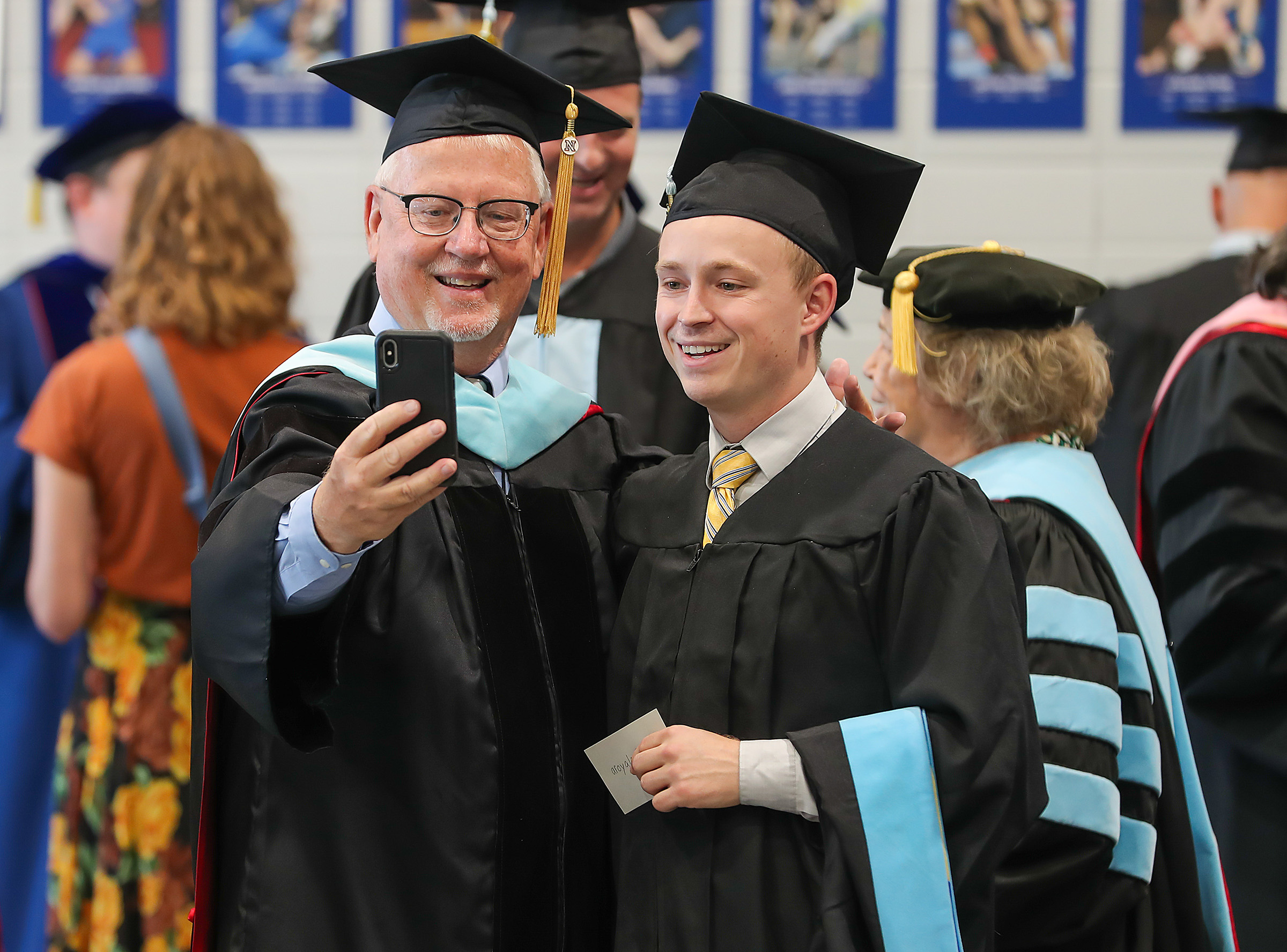 Mike Teahon poses for a photo with a graduate during a UNK summer commencement ceremony.