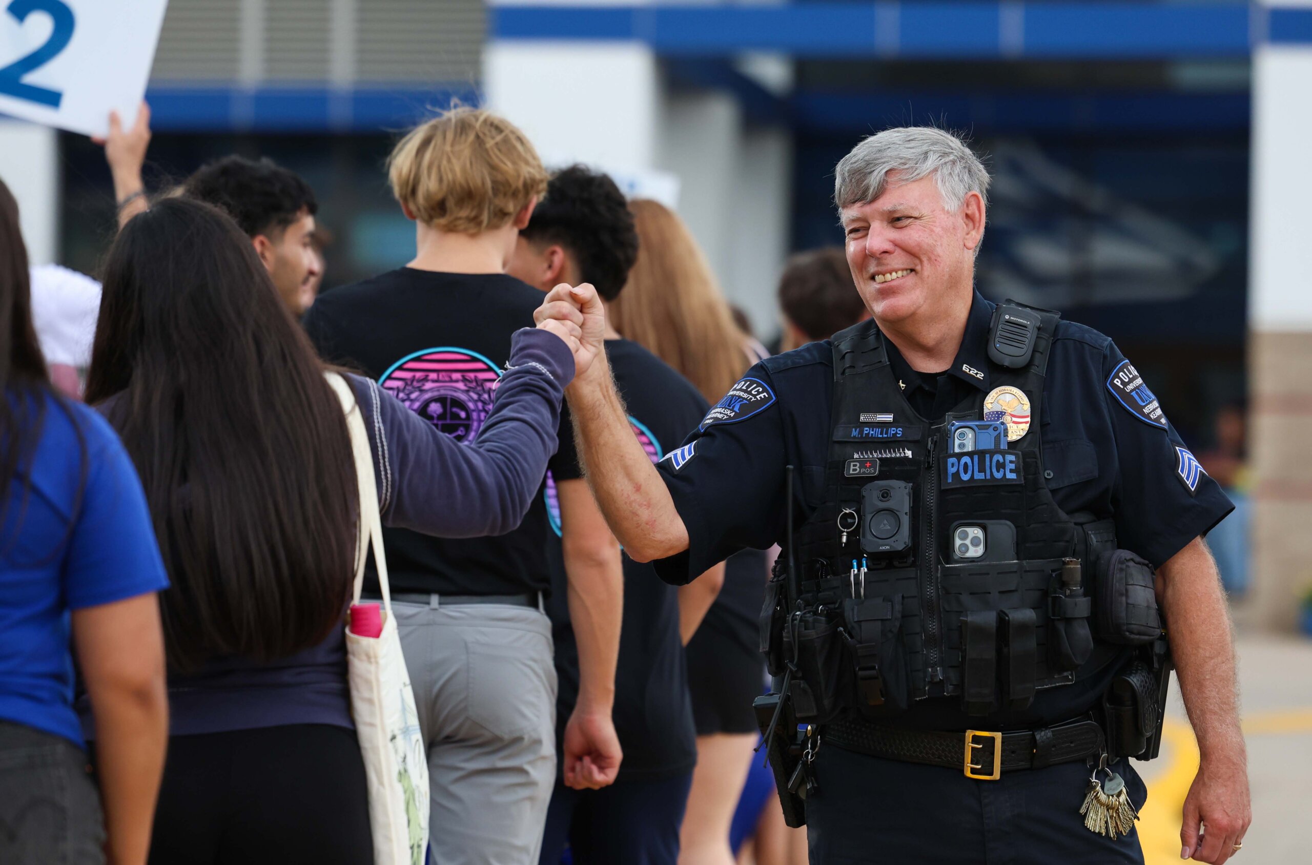 A campus police officer fist bumps a new student.