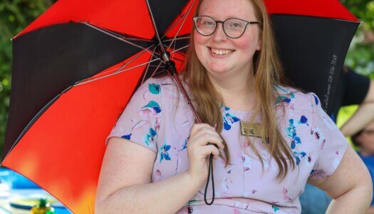 A faculty member holds an umbrella at Blue Gold Showcase.