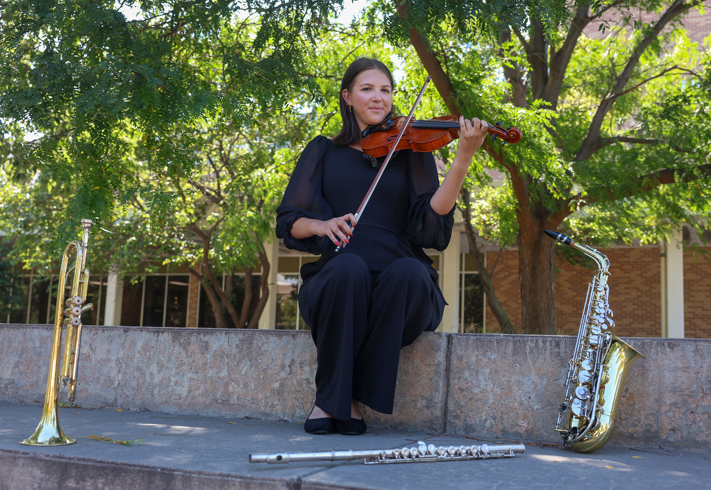 Raegen Hillman poses with instruments on the UNK campus.