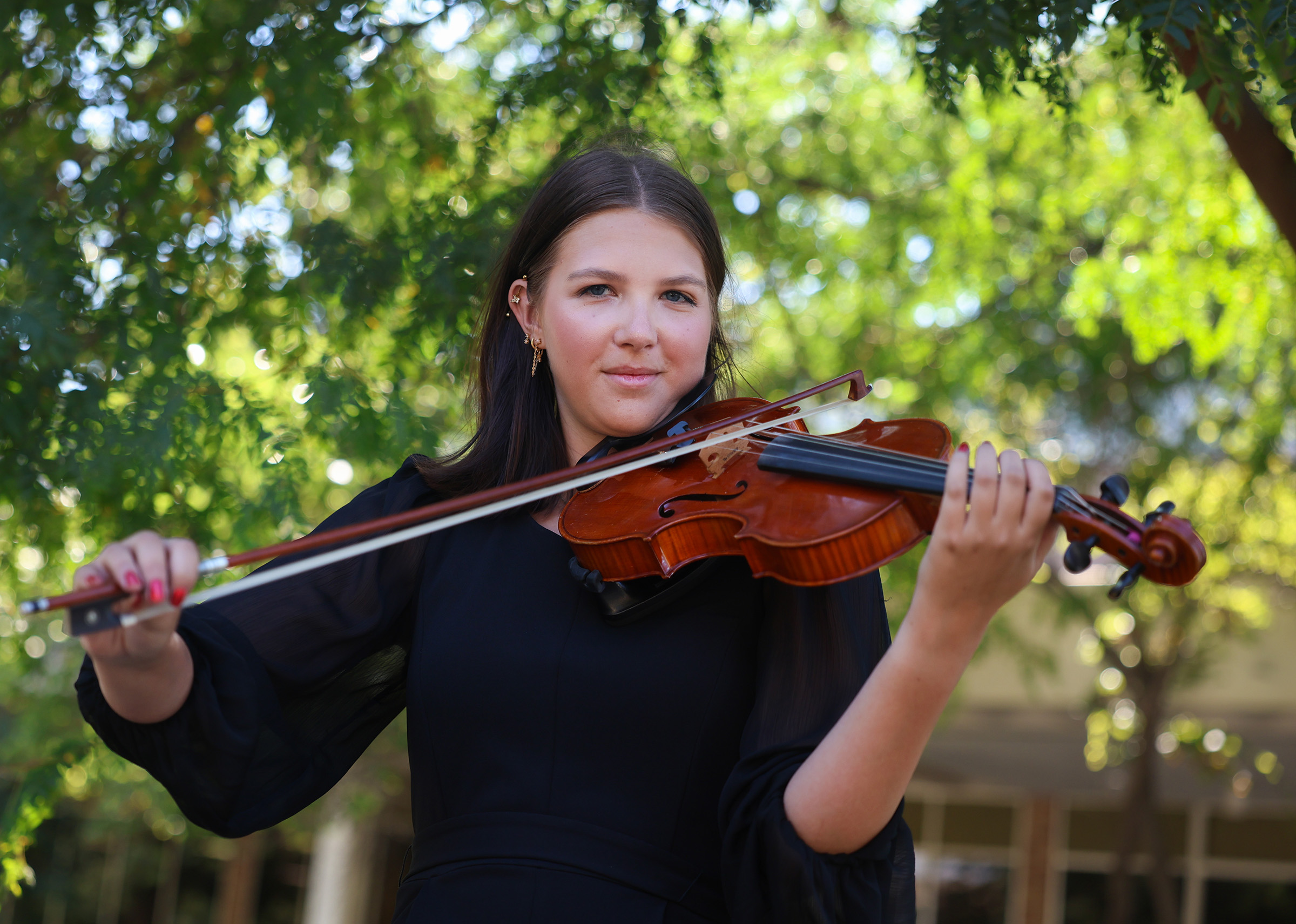 Raegen Hillman plays a violin on campus.