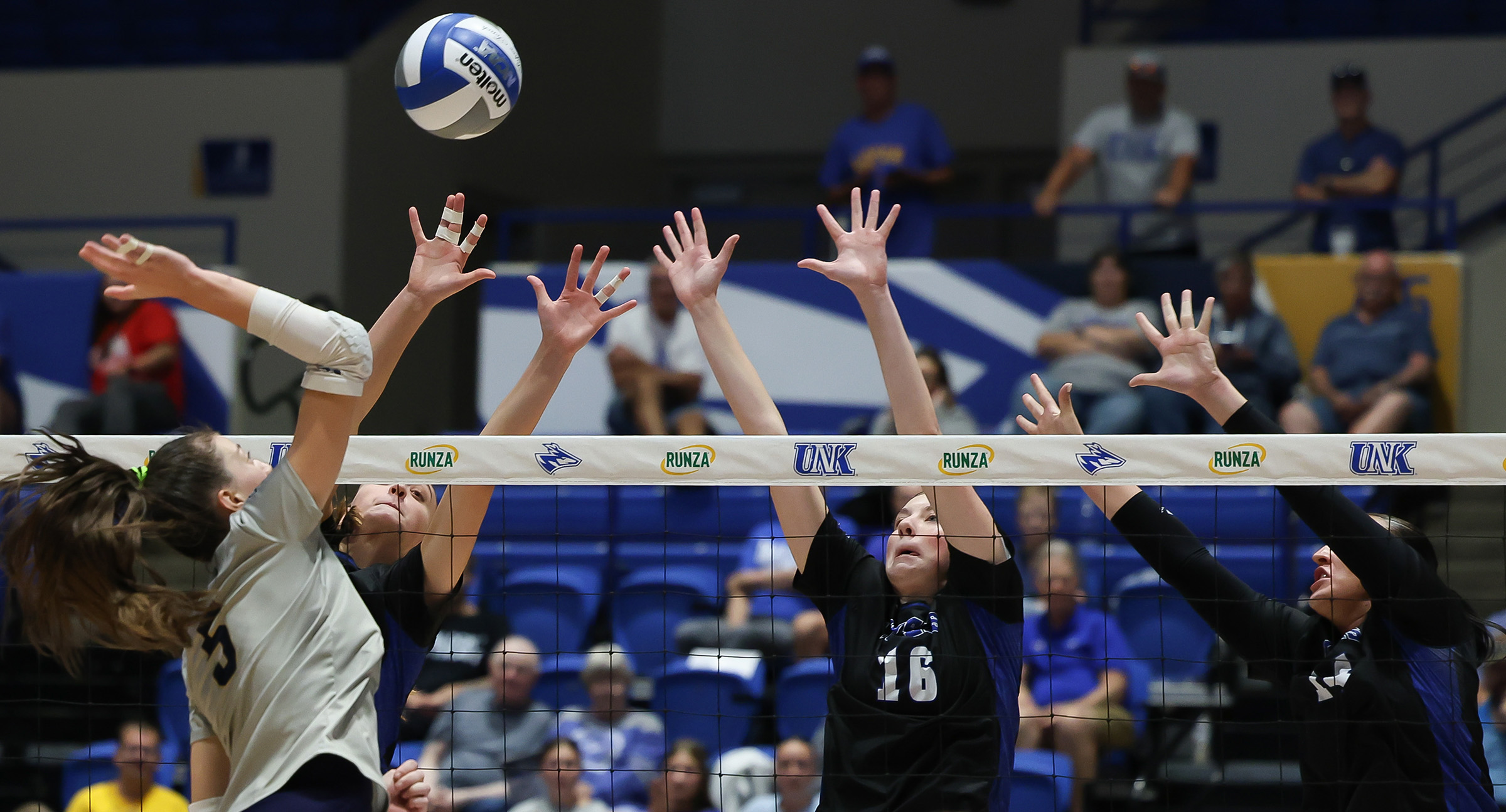 Sydney Davis and her UNK teammates elevate for a block during a match.