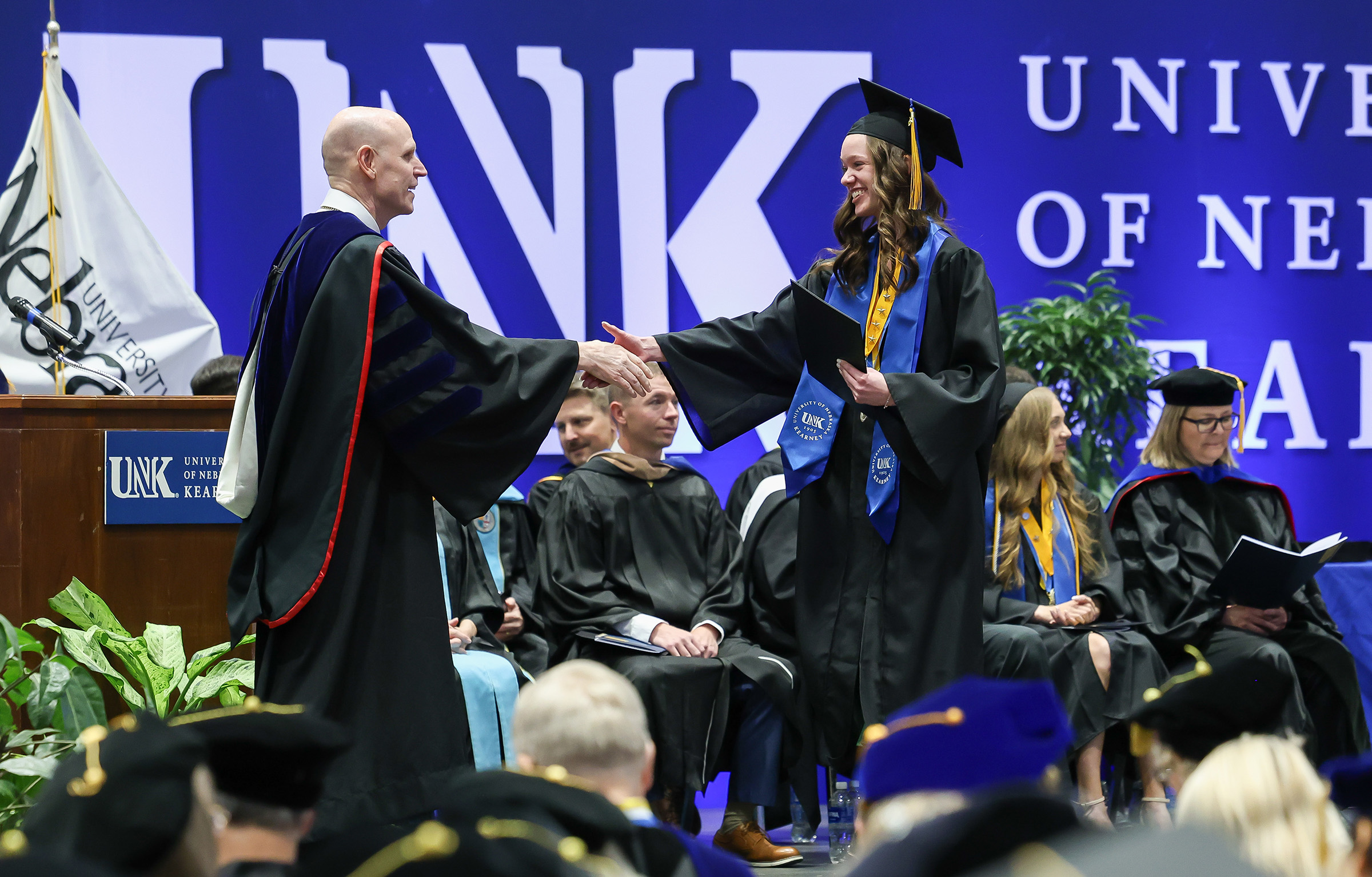 UNK Chancellor Neal Schnoor awards a degree to a student during spring commencement.