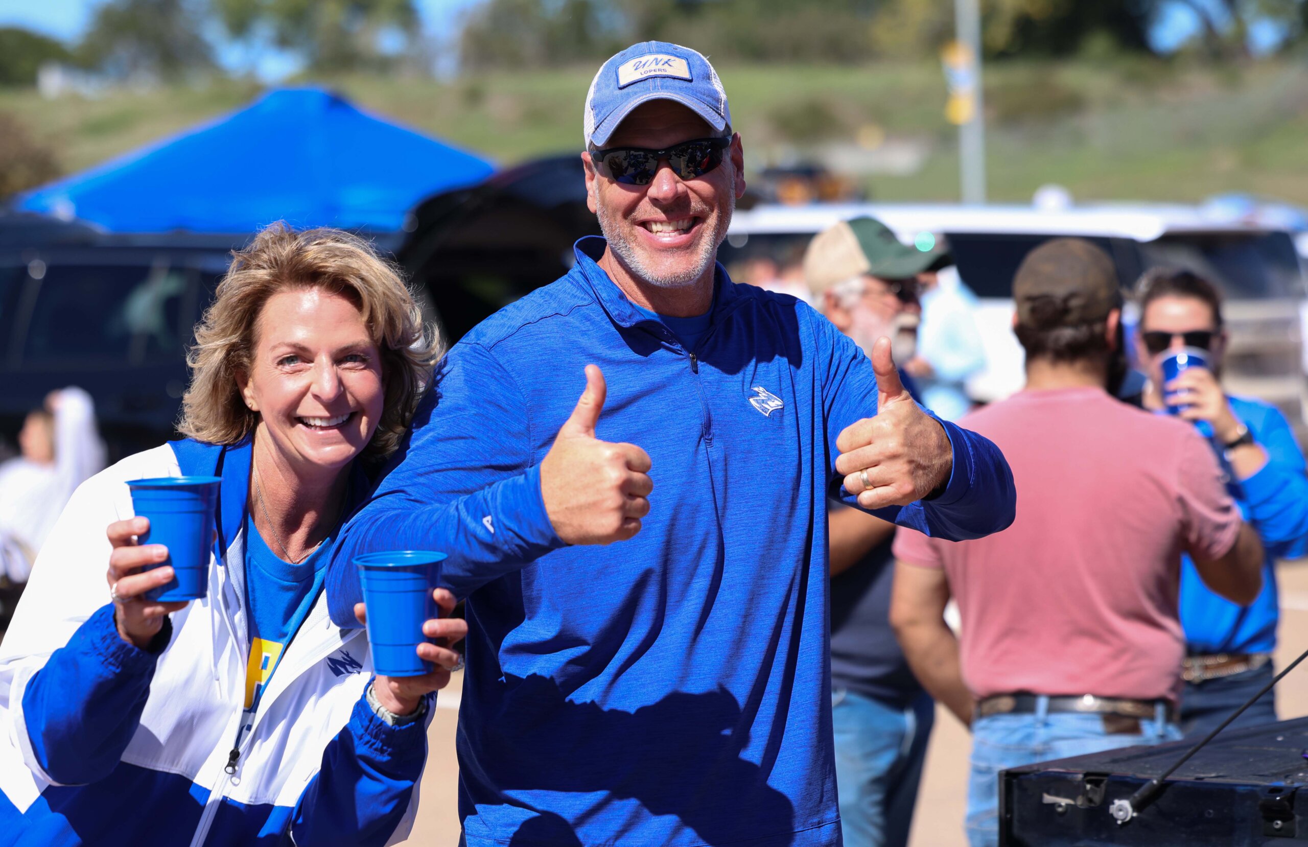 A woman and man pose at the tailgate.