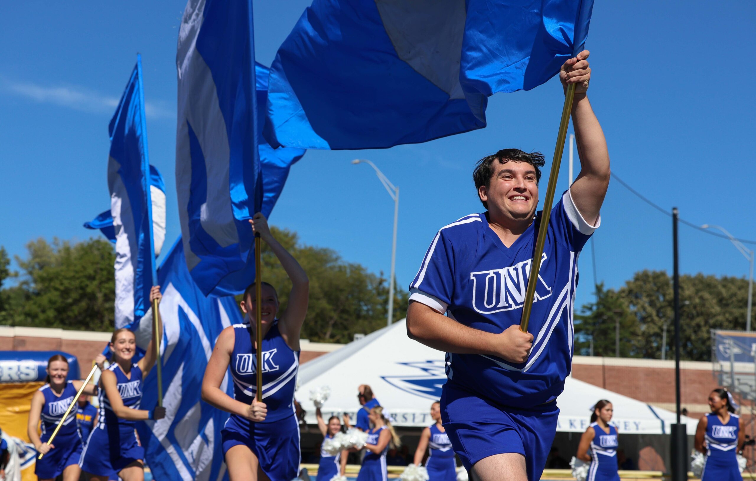 The cheer team runs flags across the field.