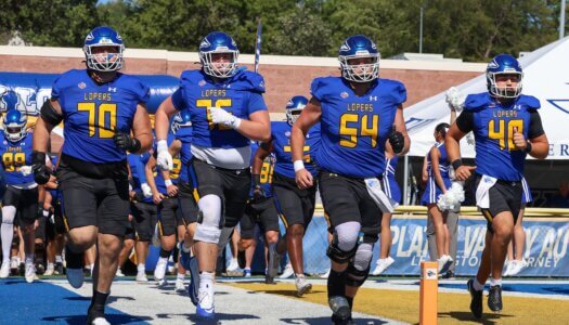 Football players run on the field.