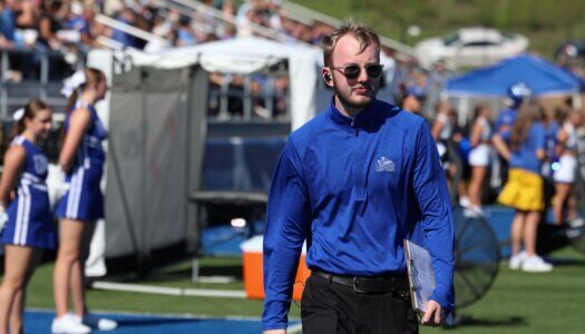 Student broadcaster Elijah Moser walks the sideline.