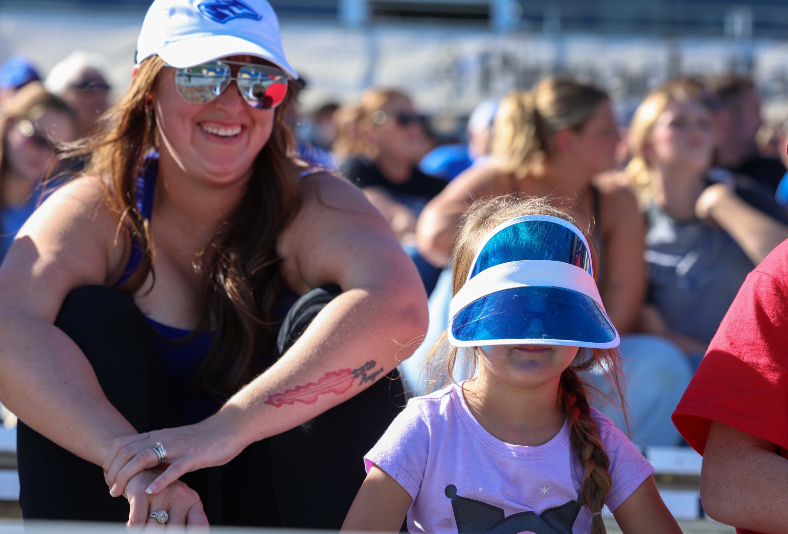A child wears a visor as her mother looks on.