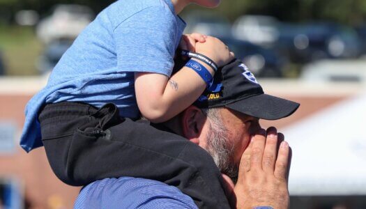 A father and son cheer at the football game.