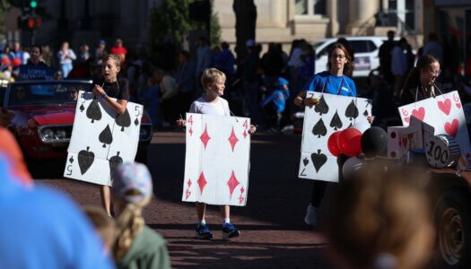 Children hold life-size playing cards in the parade.