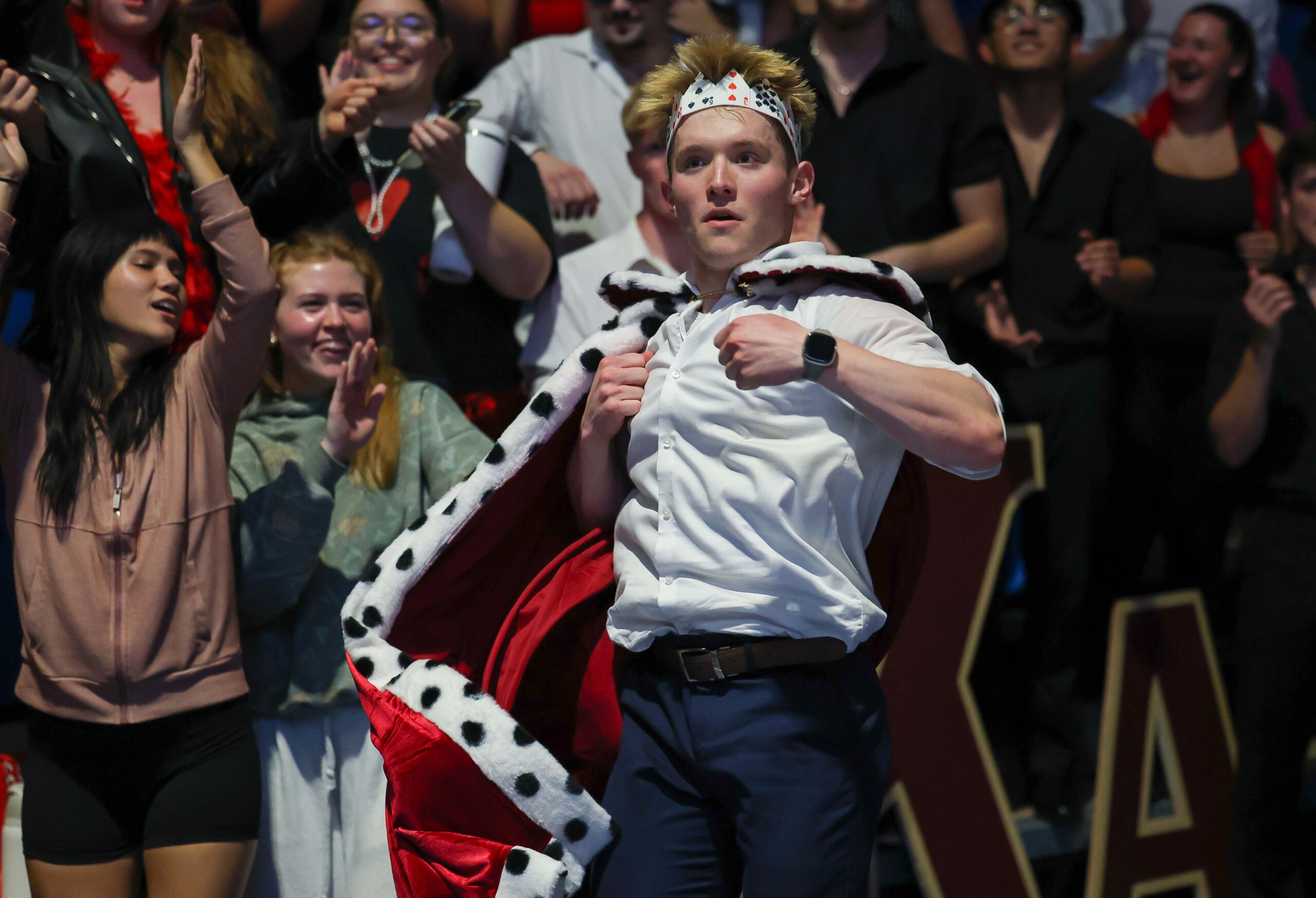 A student in a cape dances in the stands.