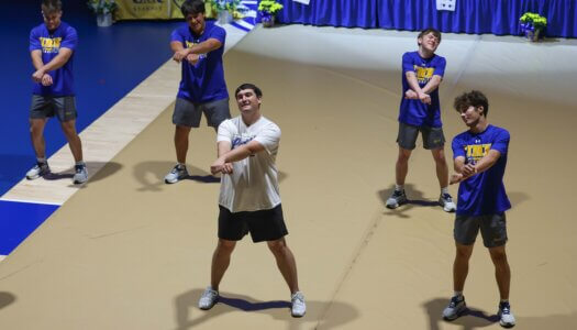 The UNK cheer team performs a routine with UNK wrestlers.